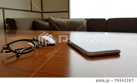木製テーブルに置かれたスマホと眼鏡 モダンなインテリア 木製テーブルに置かれたスマホと眼鏡 モダンなインテリア 79342267