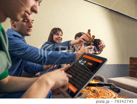 Placing bets. Group of young people, company of friends meeting together in bar, pub, outdoors. Concept of friendship, leisure activity, emotions and sport event 79342745