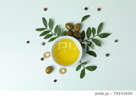 Bowl of oil, olives and twigs on white background 79343600