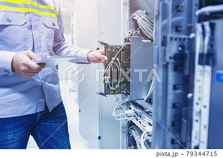 Technician using digital tablet in server room, repair card mainboard checking network link status 79344715
