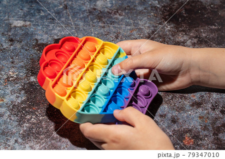 Little girl playing with rainbow colored pop it silicone toy antistress Little girl playing with rainbow colored pop it silicone toy antistress 79347010