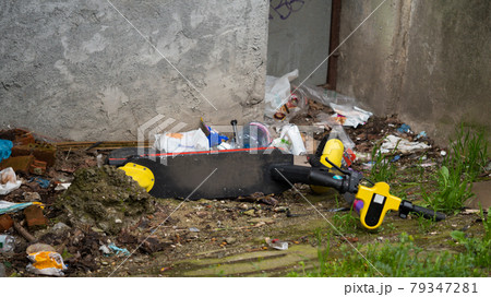 The electric scooter is thrown into the trash. The electric scooter is in pile of mess. Public transport scooter. 79347281