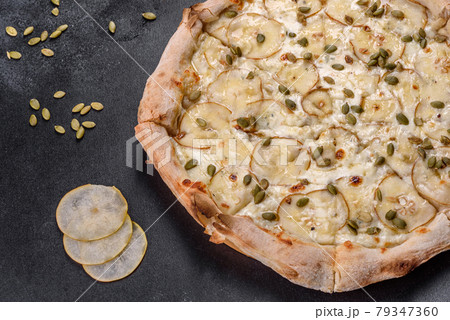 Fresh delicious Italian pizza with pear and pumpkin seeds on a dark concrete background Fresh delicious Italian pizza with pear and pumpkin seeds on a dark concrete background 79347360