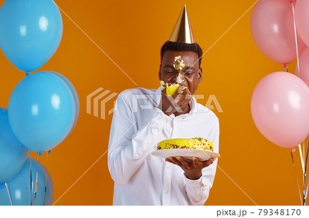 Man in cap with smeared face tasting birthday cake Man in cap with smeared face tasting birthday cake 79348170