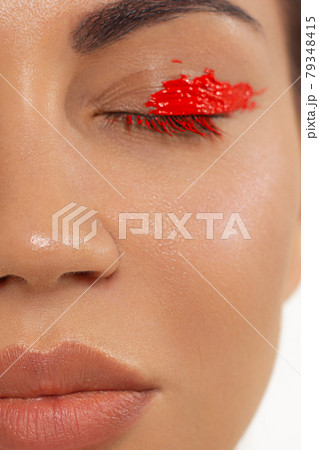 Close up beauty of a half face of a woman with wet radiant skin and big gray eyes. Fashionable natural makeup and wet facial hair. Pink lipstick with kissed lips 79348415