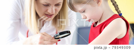 Doctor examining pigmented nevus on little girls hand with magnifying glass Doctor examining pigmented nevus on little girls hand with magnifying glass 79349309