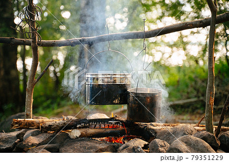 Aluminum bowlers hang over a smoking fire. 79351229