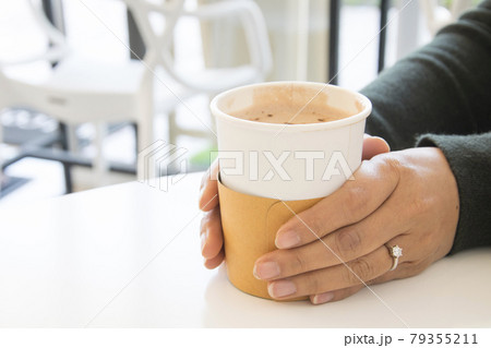 Woman with a cup of hot coffee, Hands of female holding hot drink in paper cup. Woman with a cup of hot coffee, Hands of female holding hot drink in paper cup. 79355211