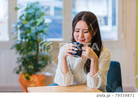 カフェでホットドリンクを飲んでくつろぐ女性 79359871