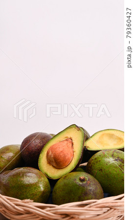 Whole and half avocado in a weaved basket. Whole and half avocado in a weaved basket. 79360427