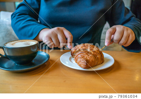 Girl eating croissant and drinking coffee Girl eating croissant and drinking coffee 79361034