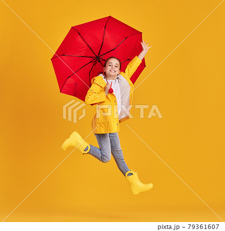 Happy kid with umbrella jumping in studio 79361607