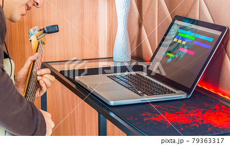 male musician enjoy recording electric guitar track on laptop computer in living room corner 79363317