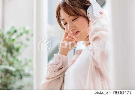 ヘッドフォンで音楽に聴き入る若い女性 79363475