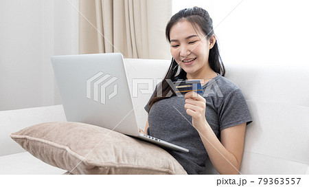 Asian woman lounging on sofa and using laptop to shop online with credit card to register for payment or online transactions, Financial transactions and Internet security, Shopping with credit card. Asian woman lounging on sofa and using laptop to shop online with credit card to register for payment or online transactions, Financial transactions and Internet security, Shopping with credit card. 79363557