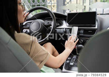 Woman sitting at the car and preparing to turning navigator her smartphone 79364529
