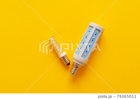 Light bulb on yellow paper background top view 79365011