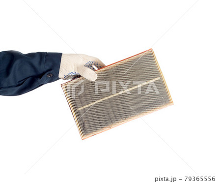 An auto mechanic holds in his hand a dirty car air filter on a white background, isolate. Filtration 79365556