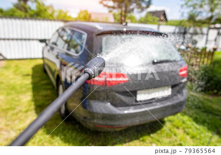 Washing a gray modern car with a manual pressure washer in a summer cottage. Car shampoo for cleaning dirt, transport 79365564