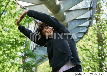 Man warming up before the workout at the spring park at the morning around the green trees Man warming up before the workout at the spring park at the morning around the green trees 79366173