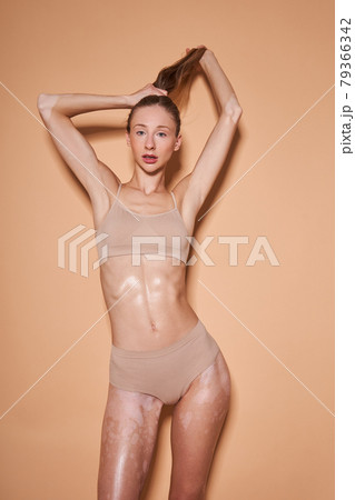 Woman in underwear holding her hair and posing at the fashionable pose over the beige wall 79366342