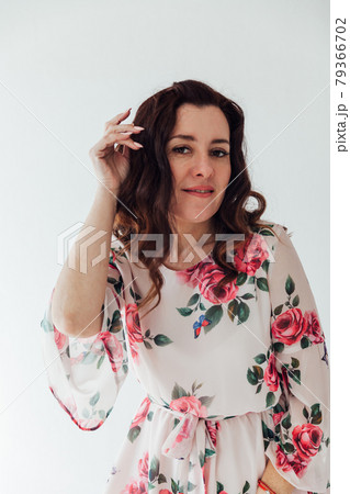 Portrait of a brunette woman in a summer dress with flowers Portrait of a brunette woman in a summer dress with flowers 79366702