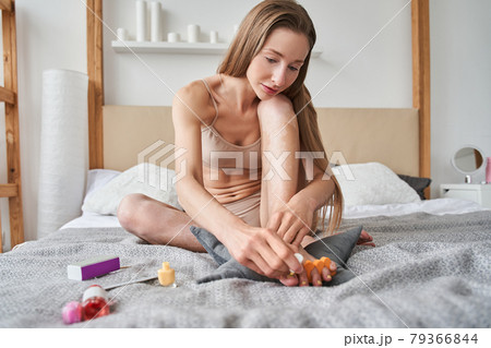 Girl with vitiligo making fashionable manicure at home while sitting at the bed 79366844