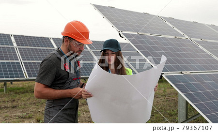 Man engineer in hard hat and inspector engineer woman learning the paper plan construction of solar panels. Alternative energy. Concept of green energy. 79367107