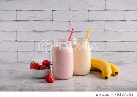 Strawberry and banana milkshakes in glass jars 79367653