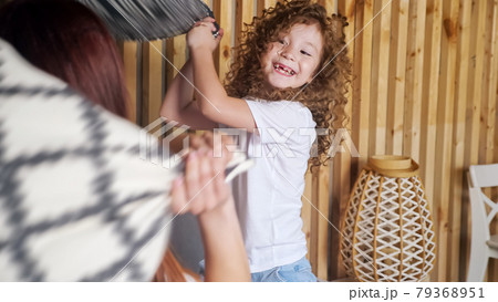 Preschooler girl fights with brunette mother with pillows 79368951
