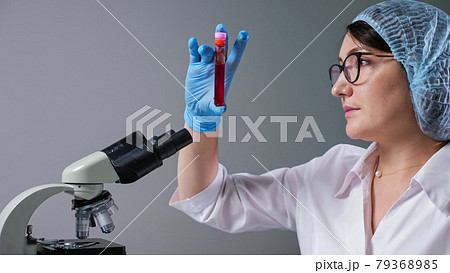 Scientist looks at sample of red liquid in modern hospital 79368985