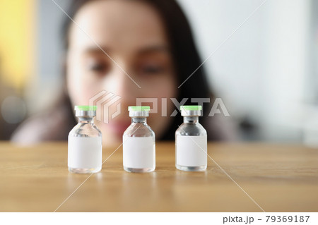 Woman looks at vaccine bottle and decides which one to choose 79369187