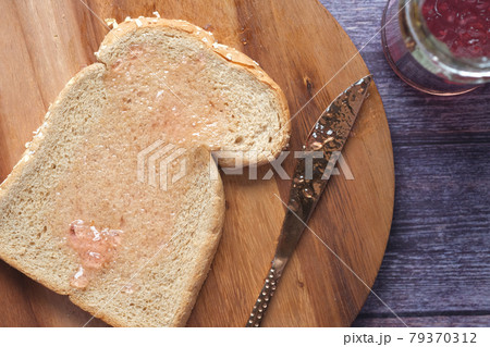 Spreading jam on on slice bread. 79370312