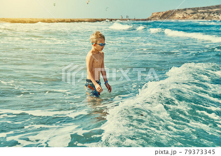 Boy in swimming goggles playing with sea waves 79373345