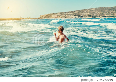 Boy in swimming goggles playing with sea waves 79373349