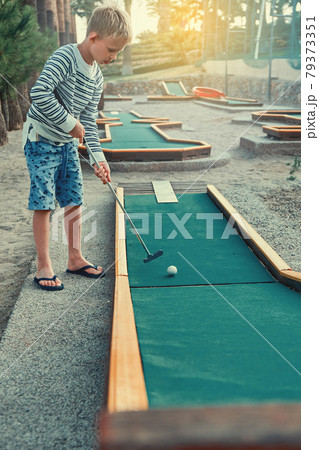 Cheerful boy playing mini golf on the territory of the hotel 79373351