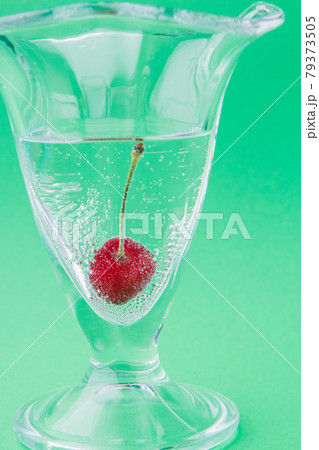 Close-up vertical shot glass cup with water and one cherry. 79373505