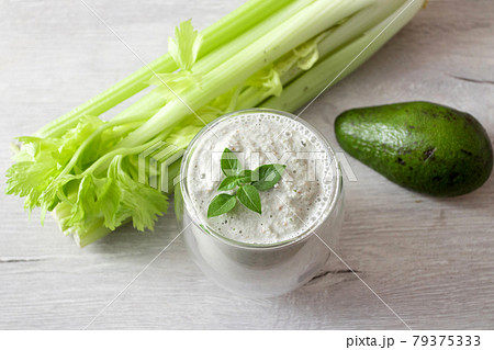 Green celery smoothie and avocado with a basil in a glass and Fresh celery stalk 79375333