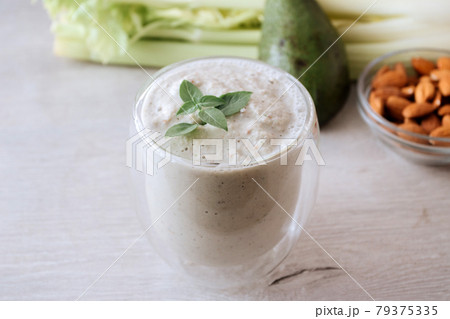 Green smoothie of celery and avocado with a basil branch in a glass. Fresh green vegetable 79375335