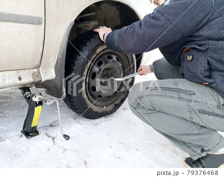 Punched and flat tire on the road. Replacing the wheel with a jack by the driver 79376468