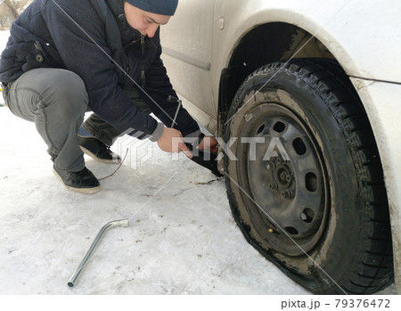 Punched and flat tire on the road. Replacing the wheel with a jack by the driver Punched and flat tire on the road. Replacing the wheel with a jack by the driver 79376472