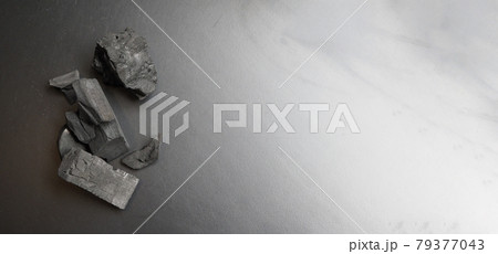 Black Charcoal on black textured floor. charcoal black carbon reesidue produced by strongly heating wood. Used for cooking or other industries. Natural wood charcoal. traditional hard wood charcoal. 79377043