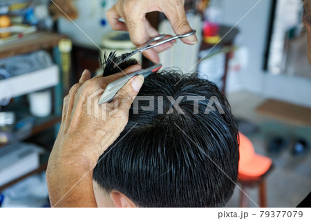 Closeup hands of hairsltylist and rear view of man having a hair cut by scissors and comb. Closeup hands of hairsltylist and rear view of man having a hair cut by scissors and comb. 79377079