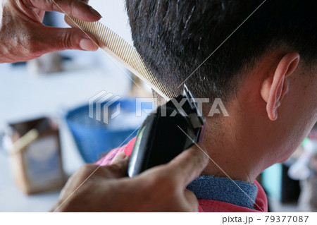 Closeup hands of hairsltylist and rear view of man having a hair cut by electrical battalion. Closeup hands of hairsltylist and rear view of man having a hair cut by electrical battalion. 79377087