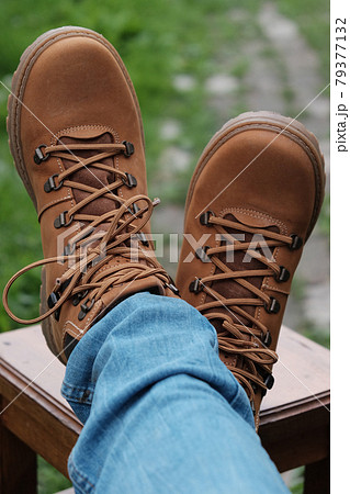Brown boots and jeans on the legs. Legs are crossed on the stool. 79377132