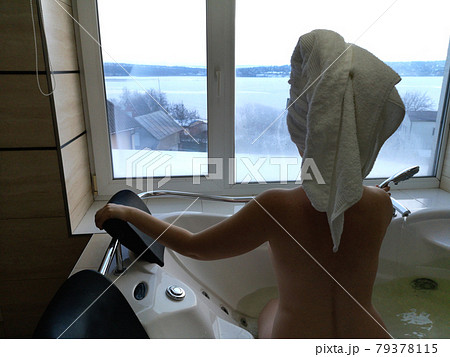 Beautiful woman in a hot tub. Jacuzzi in the hotel, panoramic view from the window in the bathroom 79378115