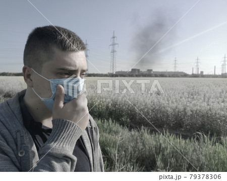 A man in a medical mask against the background of the plant. The concept of environmental pollution, ecology A man in a medical mask against the background of the plant. The concept of environmental pollution, ecology 79378306