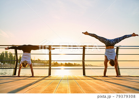 Couple doing practicing yoga together on nature outdoors . Morning exercises at the sunrise. Couple doing practicing yoga together on nature outdoors . Morning exercises at the sunrise. 79379308