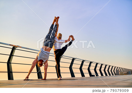 Couple doing practicing yoga together on nature outdoors . Morning exercises at the sunrise. Couple doing practicing yoga together on nature outdoors . Morning exercises at the sunrise. 79379309