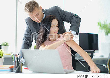 Young man in suit touching unhappy woman on shoulder in office 79379689